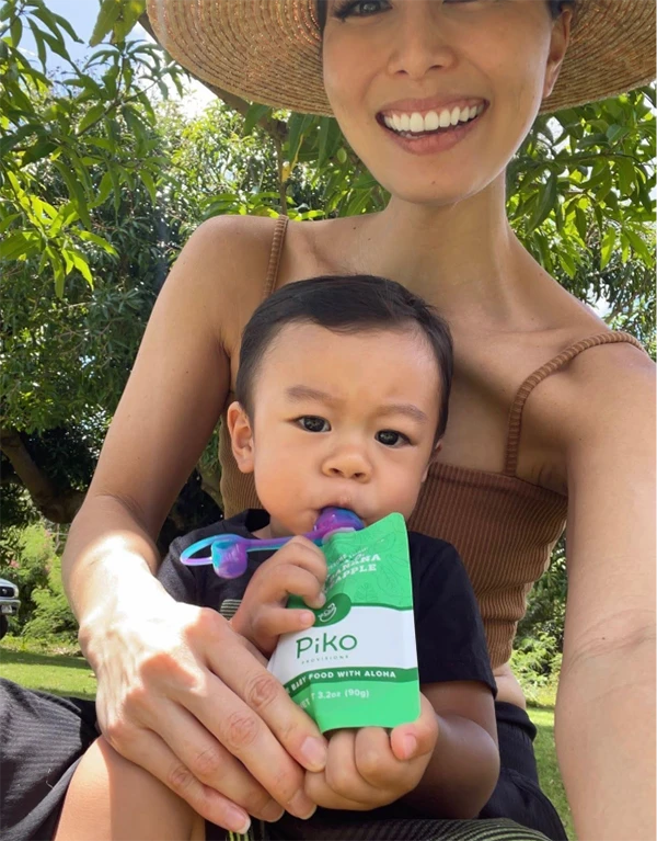 A baby eating from a Lū'au Stew Piko Provisions pouch