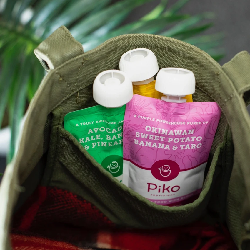 A baby eating from a Lū'au Stew Piko Provisions pouch